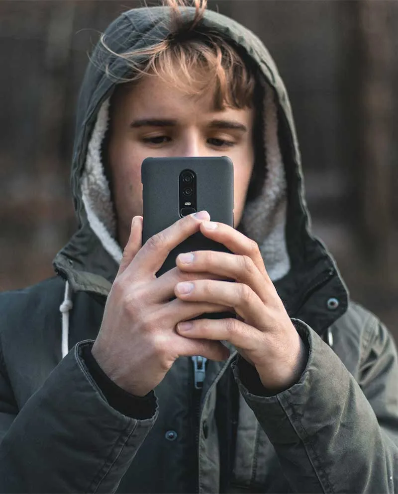 Gutt med hette tar bilde med mobiltelefonen