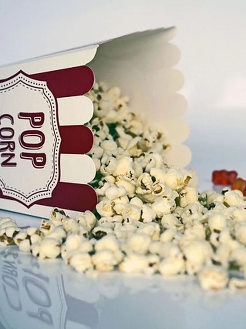 Popcornboks som velter over med popcorn og godteri