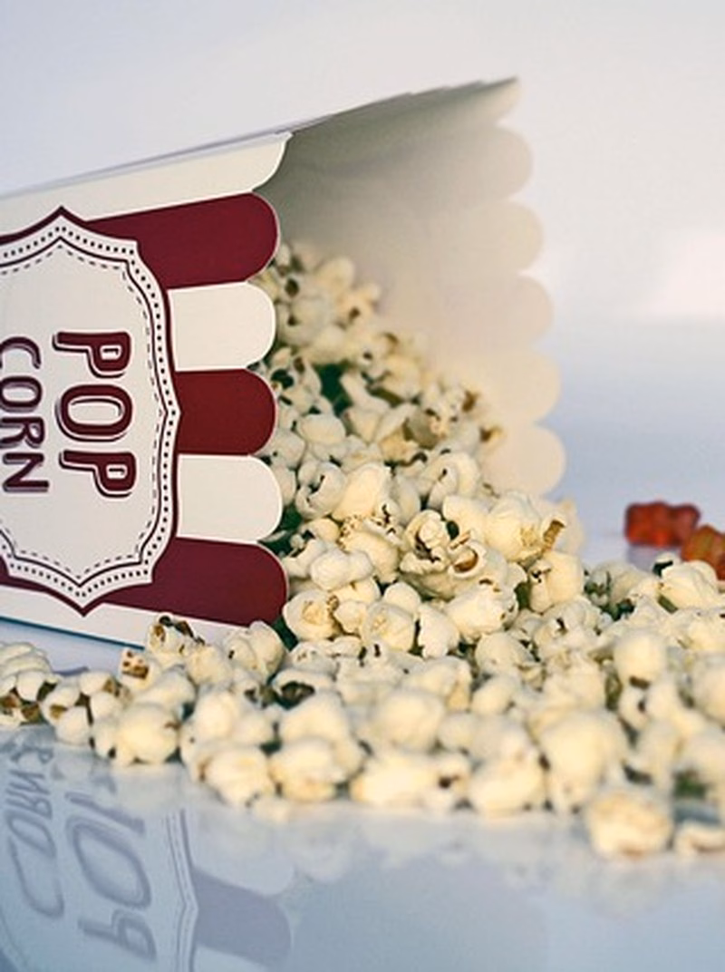 Popcornboks som velter over med popcorn og godteri